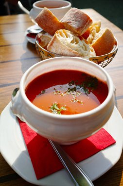 Taze sebze kremalı çorba. Beyaz kâsede servis ediliyor. Terasta da ekmek var.