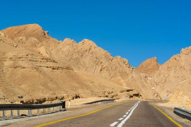 Çöldeki asfalt yol Negev, İsrail, 12. yol, çöldeki altyapı taşımacılığı, Eilat 'tan İsrail' in kuzeyine giden manzaralı dağlar.