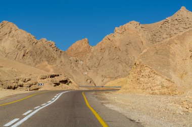 Çöldeki asfalt yol Negev, İsrail, 12. yol, çöldeki altyapı taşımacılığı, Eilat 'tan İsrail' in kuzeyine giden manzaralı dağlar.