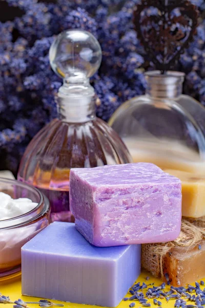 Natural healthy aromatherapy and skin treatment with organic French lavender, lavender soap, lotion and essential oils on purple background with dried lavender flowers close up