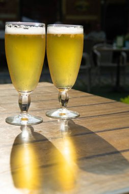 Bahçe bahçesindeki güneşli terasta servis edilen filtresiz iki soğuk bira.