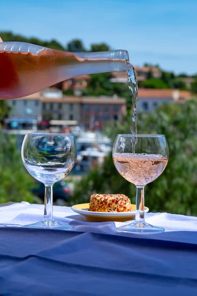 Waiter pouring cold rose wine on outdoor cafe terrace on sunny summer day in Provence, France