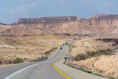Çölde asfalt yol Negev, İsrail, yol 40, çölde ulaşım altyapısı, İsrail 'de Mizpe Ramon kanyonu manzaralı dağlar.