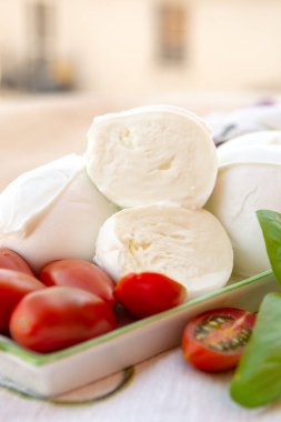 Fresh soft Italian white cheese mozzarella buffalo, original from Campania, Paestrum and Foggia regions, South Italy, served with tomatoes and fresh basil clipart
