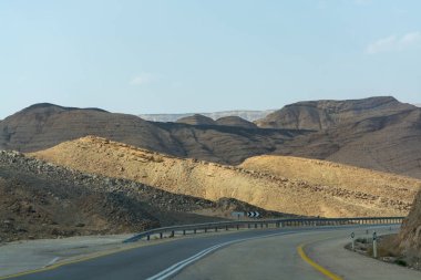 Çölde asfalt yol Negev, İsrail, yol 40, çölde ulaşım altyapısı, İsrail 'de Mizpe Ramon kanyonu manzaralı dağlar.