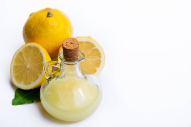 Olgun sarı Sicilya limonlarından yapılmış taze limon suyu beyaz arka planda izole edilmiş zeytin tabakasında cam şişede pişirmek için kullanılır.