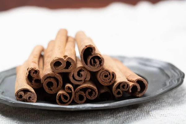 Winter food ingredient, dried aromatic cinnamon sticks on tin plate close up
