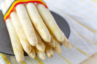 Yeni beyaz kuşkonmaz hasadı. Yüksek kaliteli Belçika kuşkonmazı. Belçika bayrağı renginde.