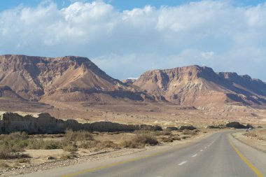 Çölde asfalt yol Negev, İsrail, yol 40, çölde ulaşım altyapısı, İsrail 'de Mizpe Ramon kanyonu manzaralı dağlar.