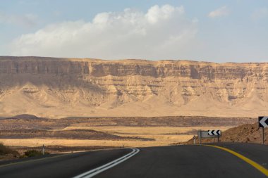 Çölde asfalt yol Negev, İsrail, yol 40, çölde ulaşım altyapısı, İsrail 'de Mizpe Ramon kanyonu manzaralı dağlar.