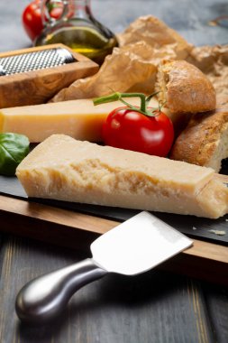 Geleneksel İtalyan yemekleri - Parmesan peynirli parmesan peyniri, peynir bıçağı, domates, fesleğen, zeytinyağı