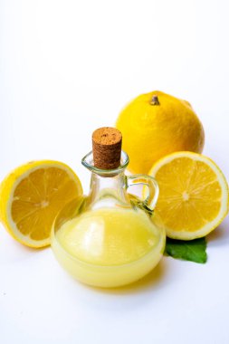 Olgun sarı Sicilya limonlarından yapılmış taze limon suyu beyaz arka planda izole edilmiş zeytin tabakasında cam şişede pişirmek için kullanılır.