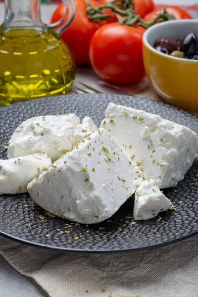 乾燥オレガノのハーブで味付け黒プレート上の新鮮な若い柔らかい白い塩フェタチーズ — ストック写真