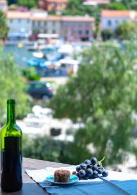 Fransa 'nın Provence kasabasında küçük bir deniz köyünde açık kırmızı şarap şişesi yumuşak keçi peyniri ve kırmızı üzüm yaz güneşli bir günde öğleden sonra dinlenmesi.