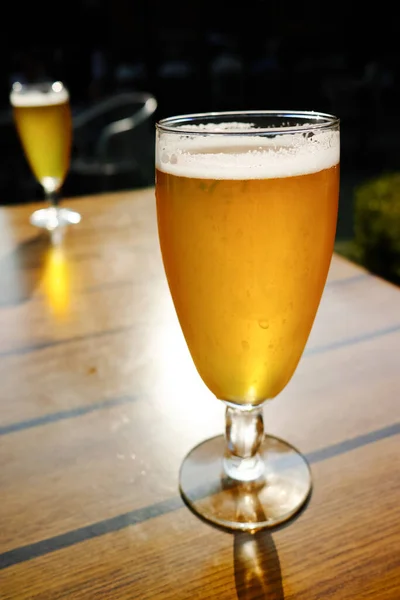 One cold light unfiltered beer in glass served on sunny outdoor terrace in garden