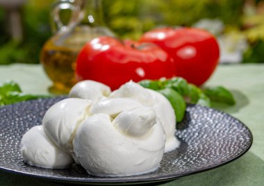 Taze fesleğen ve domatesle servis edilen yumuşak İtalyan mozzarellası şeklinde kıvrılmış.