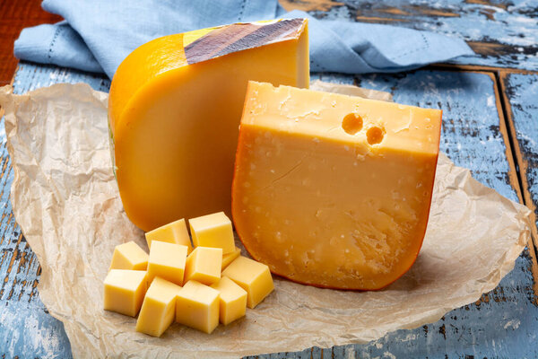 Aged and young Dutch Gouda cheese and cheese cubes blocks, tasty european food close up