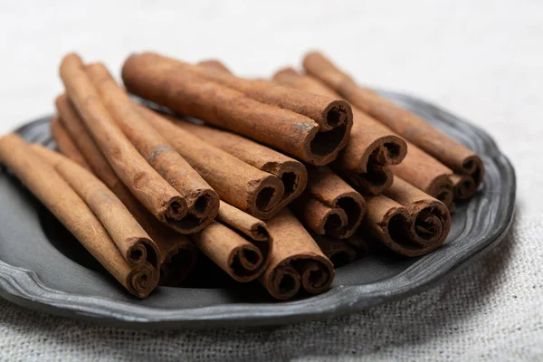 Winter food ingredient, dried aromatic cinnamon sticks on tin plate close up