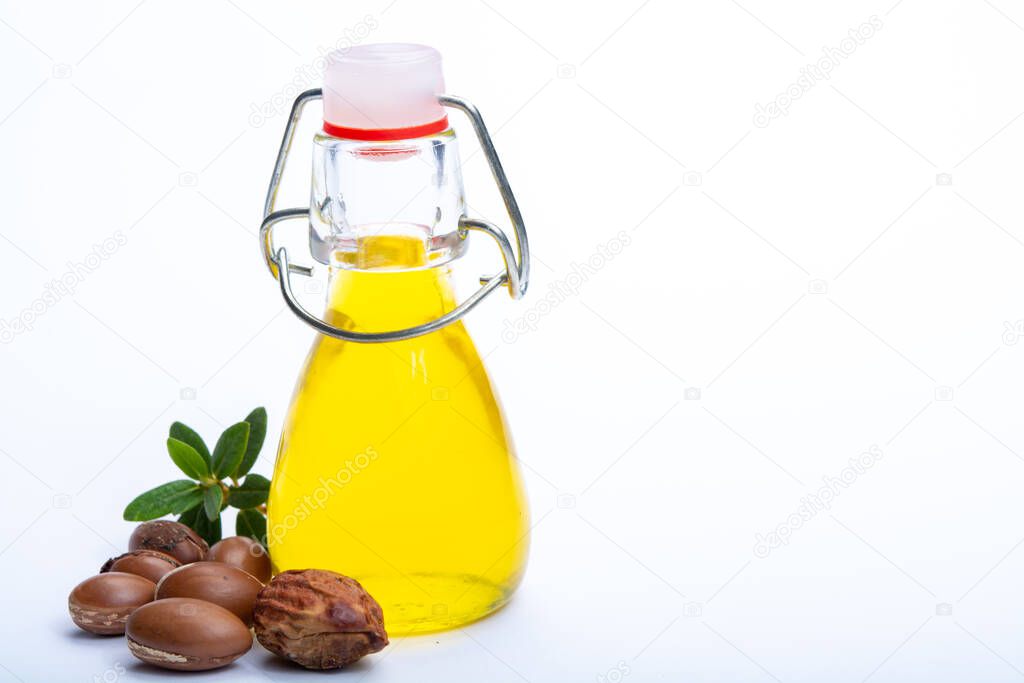 Skin and hair care product, natural argan oil in bottle and argan nuts from Morocco isolated on white background, copy space