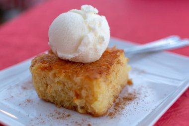 Lezzetli bir parça vejetaryen turuncu pasta ve beyaz tahtada servis edilen vanilyalı dondurma.