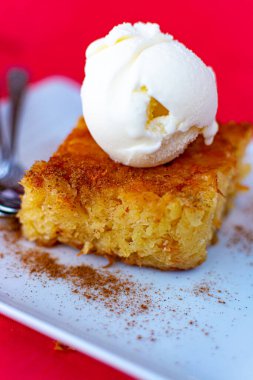 Lezzetli bir parça vejetaryen turuncu pasta ve beyaz tahtada servis edilen vanilyalı dondurma.