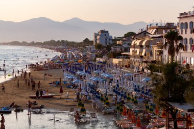 Sperlonga, Lazio, İtalya, yaz tatilinde gün batımında kumlu sahilde insan siluetleriyle manzara