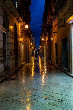 Gece Marsala 'da eski bir cadde yağmur altında sokak lambalarının yansımasıyla, Sicilya, İtalya