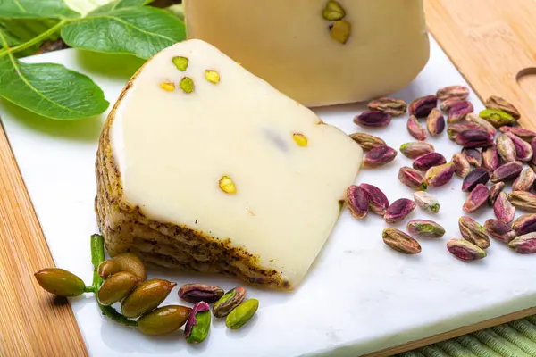 意大利产乳酪 意大利产乳酪或意大利产乳酪 与美味的绿色青铜开心果放在白色大理石盘上关闭 — 图库照片