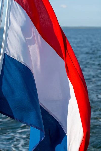 Dutch red white blue flag on sea water background close up