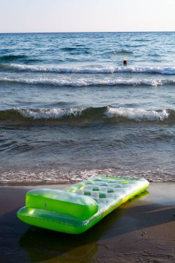 Şişme yeşil çocuklar kumsalda yüzen kötü bir oyuncak.