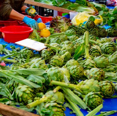 Yunanistan 'ın Nafplio kentindeki çiftçi pazarında taze taze taze enginar satışı ve temizliği