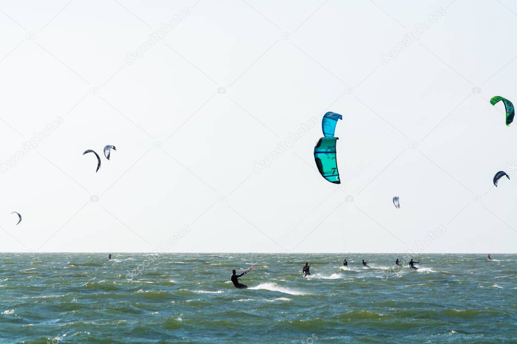 Water sport event, colorful kite surfers race in North Sea near Renesse, Zeeland, Netherlands