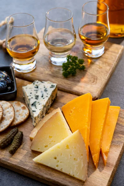 Whiskey and cheese pairing, tasting whisky glasses and plate with sliced cheeses close up