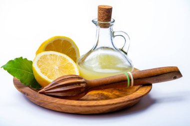 Olgun sarı Sicilya limonlarından yapılmış taze limon suyu beyaz arka planda izole edilmiş zeytin tabakasında cam şişede pişirmek için kullanılır.