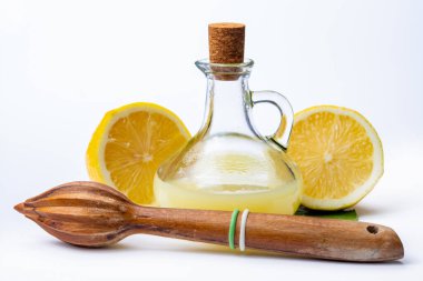 Olgun sarı Sicilya limonlarından yapılmış taze limon suyu beyaz arka planda izole edilmiş zeytin tabakasında cam şişede pişirmek için kullanılır.