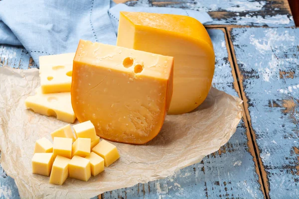 著名的硬奶酪 荷兰古达奶酪和法国羊绒面包 成块地放在纸上 — 图库照片