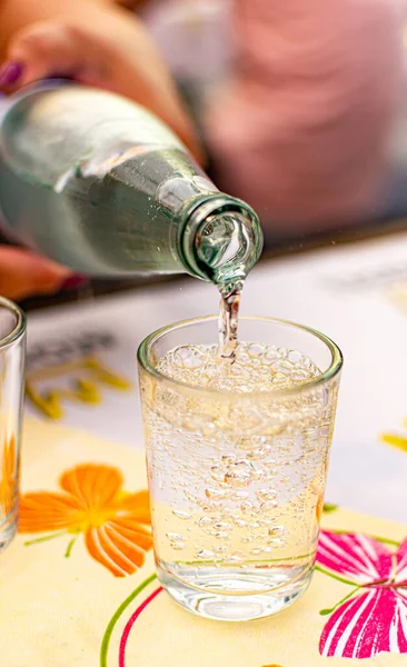 Pouring of cold mineral water from bottle in glass