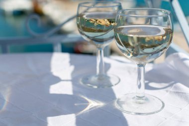 Balkonda servis edilen beyaz şarap cam masada, deniz manzaralı.