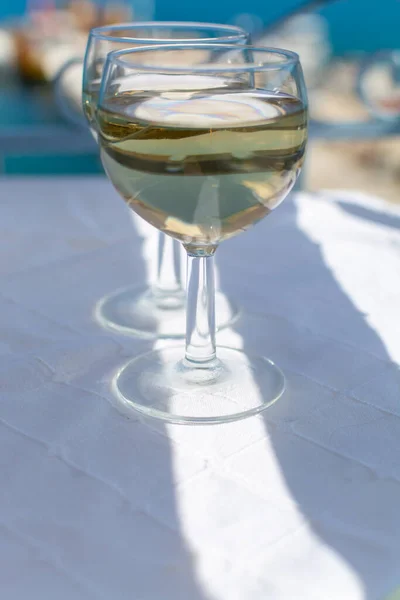 White wine served outside on balcony on glass table with sea view close up