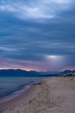 Alcamo Marina 'daki kumlu sahil üzerinde güneş doğarken gri-mavi bulutlar, İtalya' nın Sicilya kentinde küçük bir kasaba, yaz tatilinde tatil yeri.