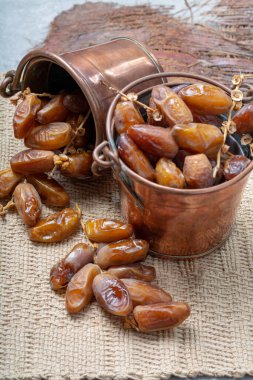 Authentic Tunisian Deglet Nour dried dates with soft honey-like taste in copper buckets clipart