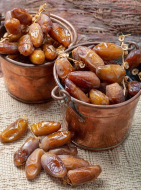 Authentic Tunisian Deglet Nour dried dates with soft honey-like taste in copper buckets clipart