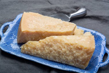 Peynir koleksiyonu, İtalyan parmesan peyniri. Mavi tahtada iki parça halinde servis edilmiş. Bıçakla yakından.