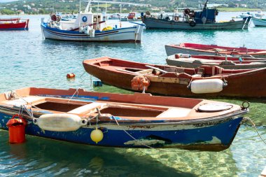 İskeleli deniz manzarası, şeffaf suyu olan sakin deniz limanı ve geleneksel Yunan balıkçı tekneleri.