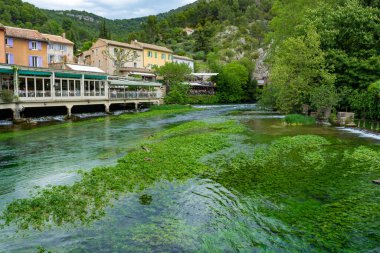 Fransa 'nın güneyinde, Sorgue Nehri' nin zümrüt yeşili sularıyla küçük turistik bir kasaba olan şair Petrarch Fontaine-de-vaucluse görülüyor.