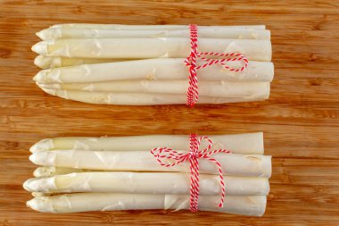 Yeni beyaz kuşkonmaz hasadı. Bahar mevsiminde iki demet yüksek kaliteli çiğ kuşkonmaz.