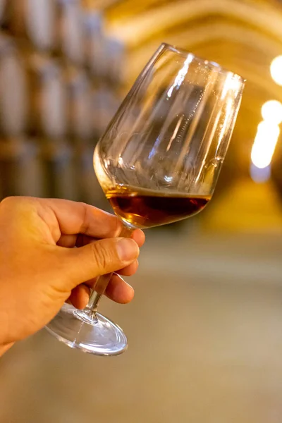Tasting of fortified dry or sweet marsala wine in vintage wine cellar with old oak barrels in Marsala, Sicily, Italy, wine glass with wine