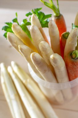 Yeni beyaz kuşkonmaz hasadı, yüksek kaliteli çiğ kuşkonmaz, bahar mevsiminde plastik kovada havuç ve satış, yakın pişirmeye hazır.