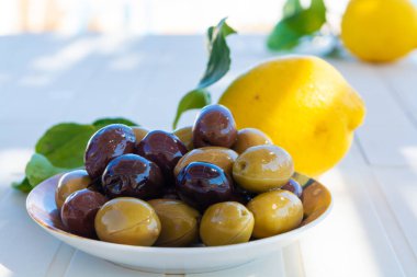 Zeytinyağlı İtalyan yeşil ve siyah zeytinleri beyaz masada servis edilir.