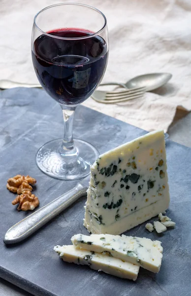Piece of French blue cheese Roquefort, made from sheep milk in caves of Roquefort-sur-Soulzon and glas with red wine